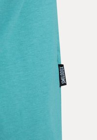 Turkos textil med en slät yta; inkluderar en svart etikett med inskriptionen "SILLOOX" fäst vid kanten.