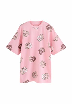 Pink T-shirt featuring a repeated pretzel heart pattern in various shades of brown and cream, with a round neckline and short sleeves.