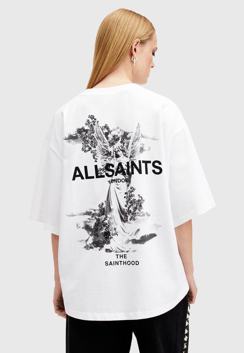 Camiseta blanca de gran tamaño con un gráfico negro de un ángel y elementos florales en la parte posterior, con el texto "ALLSAINTS LONDON".
