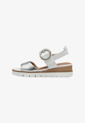 Sandalo bianco e argento con una spessa suola platform bianca. Presenta una fascia metallica e un accento rotondo vicino alla caviglia per una vestibilità sicura.