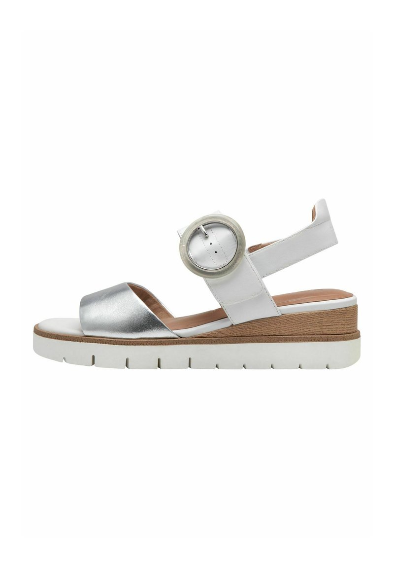 Sandalo bianco e argento con una spessa suola platform bianca. Presenta una fascia metallica e un accento rotondo vicino alla caviglia per una vestibilità sicura.
