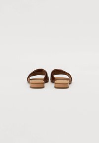 Sandali in pelle marrone con suola in legno piatta, caratterizzati da un design aperto sulla punta e cinghie incrociate per la ventilazione. Nessun logo o motivo visibile.