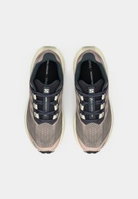 Ζευγάρι μπεζ και μαύρα παπούτσια τρεξίματος Salomon Aero Blaze με μαύρα κορδόνια, φωτογραφημένα από πάνω πάνω σε λευκό φόντο.