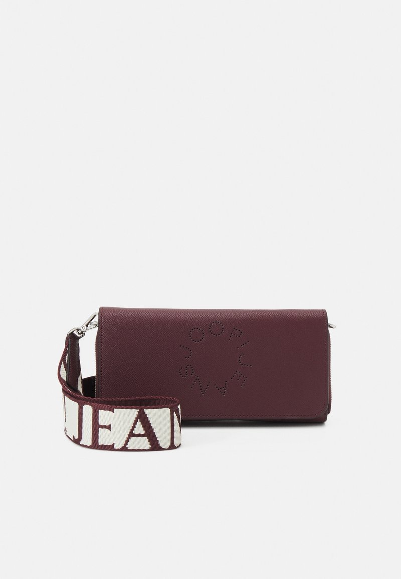 Burgundy leather clutch with circular perforated logo and detachable fabric strap featuring bold white and burgundy text.