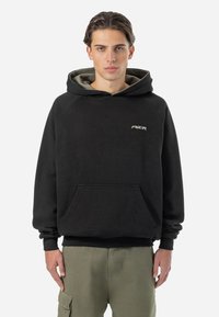 Zwarte hoodie met een buidelzak, een capuchon met trekkoord en contrasterend groene voering, met een klein wit logo op de borst.