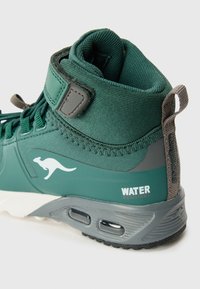 Grüner wasserdichter High-Top-Schuh mit Obermaterial aus Textil, grauen Akzenten, strukturiertem Kragen und Logo. Verfügt über eine Schlaufe und ein Schnürdesign.