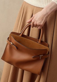 Borsa in pelle marrone con un esterno liscio e foderatura in camoscio, caratterizzata da una forma strutturata, doppi manici e accenti in metallo argentato.