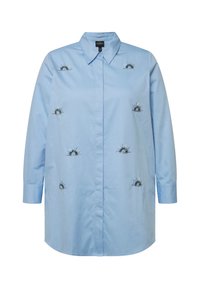 Camicia azzurro chiaro con bottoni e maniche lunghe, caratterizzata da disegni di raggi di sole ricamati in blu e argento sulla parte anteriore. Tessuto di cotone liscio.