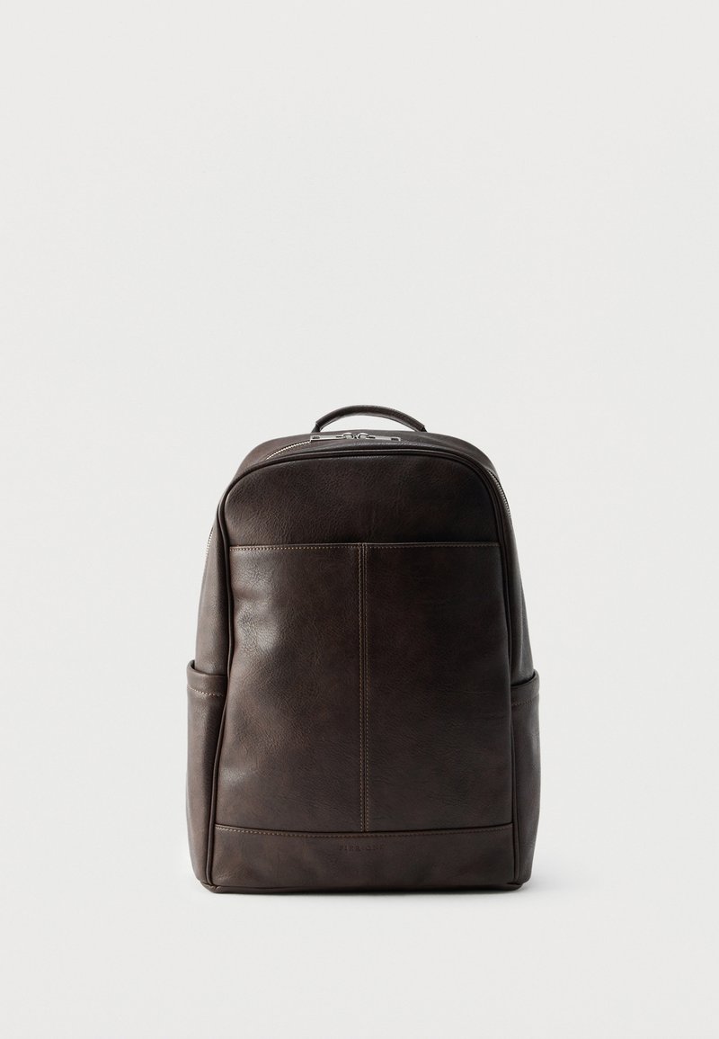 Καφέ δερμάτινο σακίδιο με λεία υφή, στρογγυλεμένη κορυφή και μπροστινή τσέπη. Διαθέτει χειρολαβή στην κορυφή και κλείσιμο με φερμουάρ. Απλός σχεδιασμός.