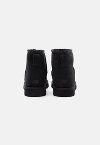 Černé semipreforované kotníkové boty s měkkou fleecovou podšívkou, gumovou podrážkou a zesíleným podpatkem. Na zadní straně se nachází logo a robustní švy.