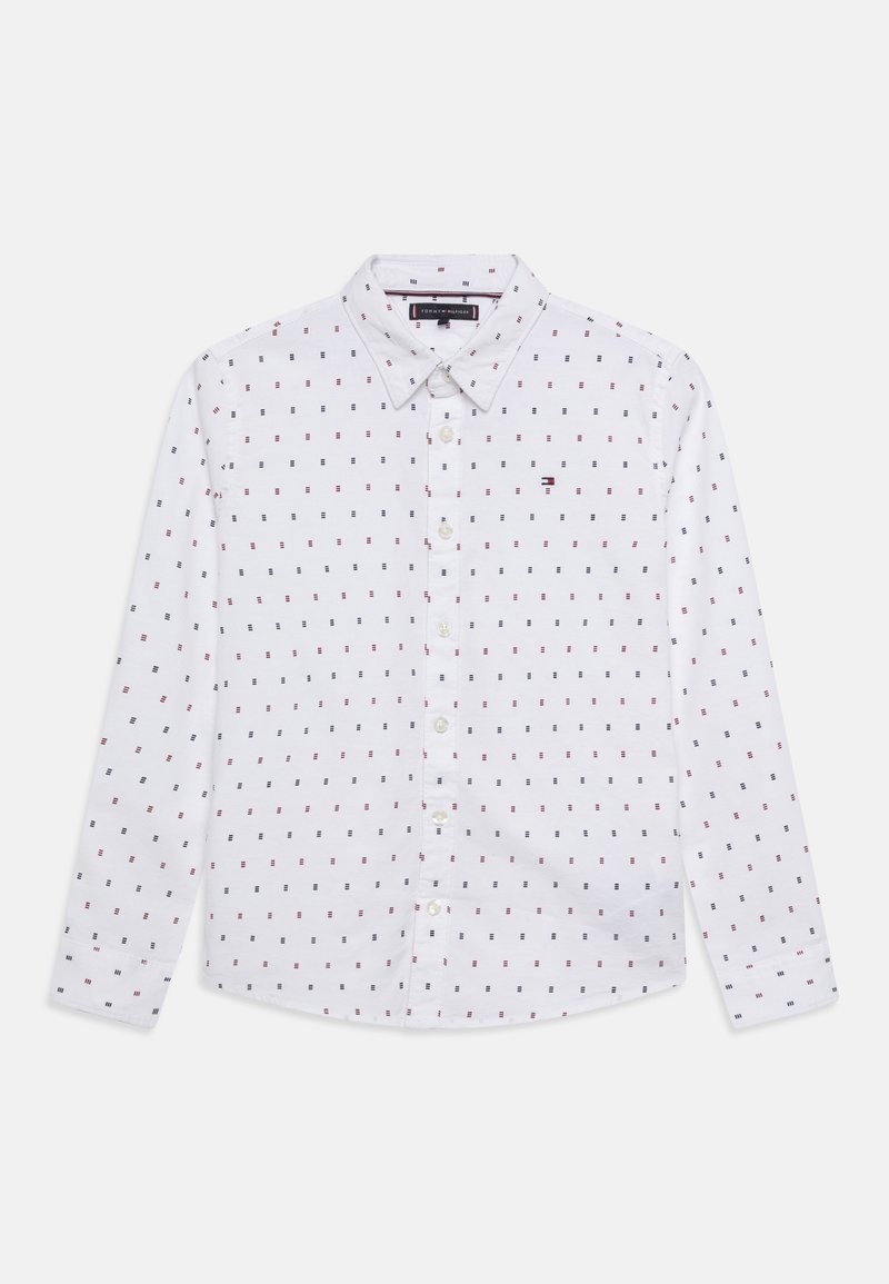Chemise blanche à manches longues avec boutons, ornée de petits motifs carrés rouges et bleu marine, avec un col classique, présentée à plat sur un fond blanc.