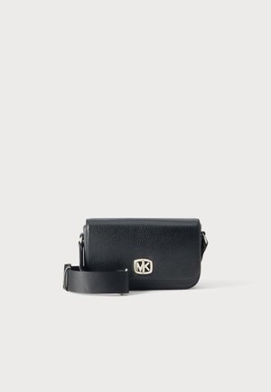 Sac bandoulière en cuir noir avec une large sangle réglable et un logo MK argenté sur le rabat avant, sur un fond clair uni.