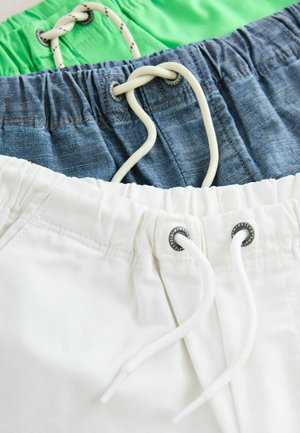 Tre paia di pantaloni corti impilati: verde, blu denim e bianco. Ognuno ha una vita elastica con lacci e dettagli hardware a contrasto.