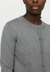 Gray knitted cardigan with a round neckline, button closure featuring beige buttons, and ribbed cuffs. Smooth texture with a fitted shape.