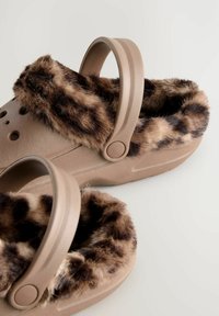 Ruske lesene cipele s pahuljastom podstavom u leopard-uzorku i plastičnom trakom. Materijal je gladak s ventilacijskim otvorima sa strane.