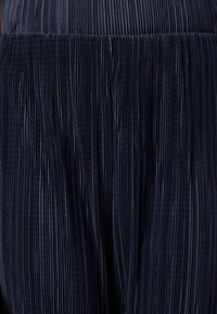 Tissu plissé bleu marine avec des rayures verticales, texture douce, taille élastique, adapté aux vêtements fluides ou aux jupes.