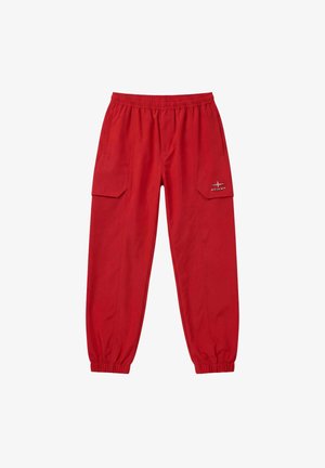 Pantaloni cargo rossi con vita elastica e polsini, tasche laterali e piccolo logo riflettente sulla patta della tasca sinistra.