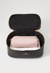 Svart glidelåsmappe med gullakenter, med en rosa, teksturert indre rom for oppbevaring. Merket leser "ANNA FIELD."