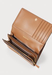 Portafoglio in pelle marrone chiaro con più scomparti per carte, hardware dorato, una tasca con zip e il logo impresso in oro. Texture liscia.