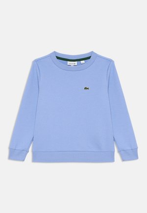 Sweatshirt à col rond à manches longues bleu clair avec des poignets et un ourlet côtelés, arborant un petit logo crocodile vert de Lacoste sur la poitrine.