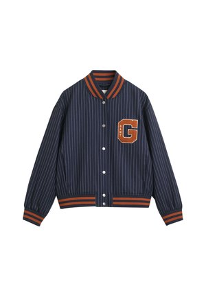 Giacca bomber a righe blu navy con collare e polsini a coste arancioni. Presenta una toppa di feltro con la lettera "G" sul lato sinistro del petto e una chiusura a bottoni a pressione.