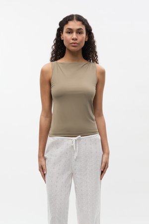 Haut sans manches en kaki en matière lisse et extensible, associé à un pantalon blanc léger brodé avec une taille à cordon.