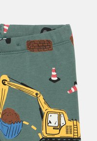 Πράσινο ύφασμα με μοτίβα θεματικά κατασκευής, που περιλαμβάνουν ένα εκσκαφέα, κώνους και τούβλα σε αποχρώσεις καφέ  και κίτρινου. Μαλακή υφή.