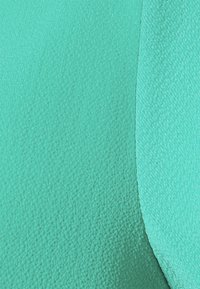 Getextureerde teal stof met een licht glanzend, glad oppervlak. Het materiaal vertoont kleurvariaties en een subtiel weefpatroon.