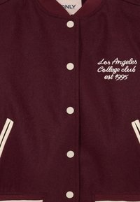 Bordo sporta jaka ar baltām pogām, baltām oderēm kabatām un izšūtu uz krūtīm tekstu "Los Angeles College club est 1995".