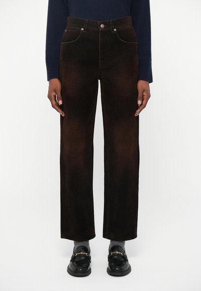 Pantaloni in velluto a coste marroni con vita alta, design a gamba dritta, cuciture visibili e tasche anteriori. Abbinati a mocassini neri.