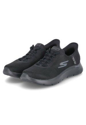 Zapatillas deportivas de malla negra con un diseño ligero, punta redonda, cordones en la parte frontal y una suela acolchada con detalles texturizados.