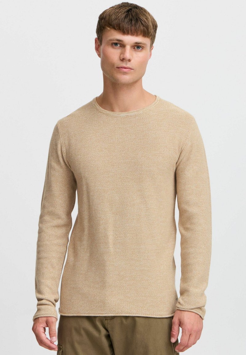 Beiger strukturierter Strickpullover mit Rundhalsausschnitt und langen Ärmeln, der ein dezentes Muster und einen geraden Saum aufweist.