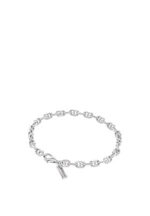 Bracelet chaîne en argent avec des maillons ovales et une petite étiquette rectangulaire près du fermoir gravée du texte de la marque sur fond blanc.