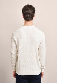 Weißer gestrickter Pullover mit strukturiertem Muster, gerippten Bündchen und Saum. Runder Halsausschnitt und lange Ärmel.