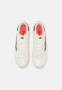 Scarpe sportive bianche con accenti neri, superiore testurizzato e soletti rossi; presentano una chiusura con lacci e un design snello.