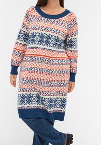 Knittröja med rund hals, med ett flerfärgat geometriskt mönster i röd, blå och krämfärg. Ribbad muddar och nederkant.