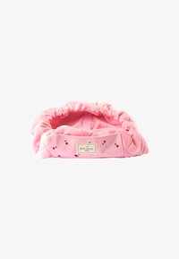 Alfombrilla plana acolchada rosa con un borde recogido y motivos de cereza, con una etiqueta que dice "The Flat Lay Co. London" adjunta.