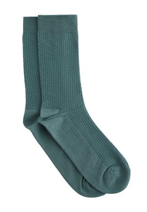 Paire de chaussettes mi-mollet turquoise avec un motif en zigzag texturé sur la jambe et un tissu lisse sur le pied et les zones des orteils.