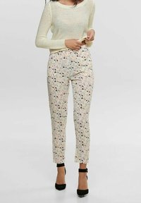 Blumenmuster-Hosen in sanften Pastellfarben mit eng anliegender Passform, ausgestattet mit einer glatten Textur und knöchellanger Gestaltung. Kombiniert mit einem leichten Strickpullover.