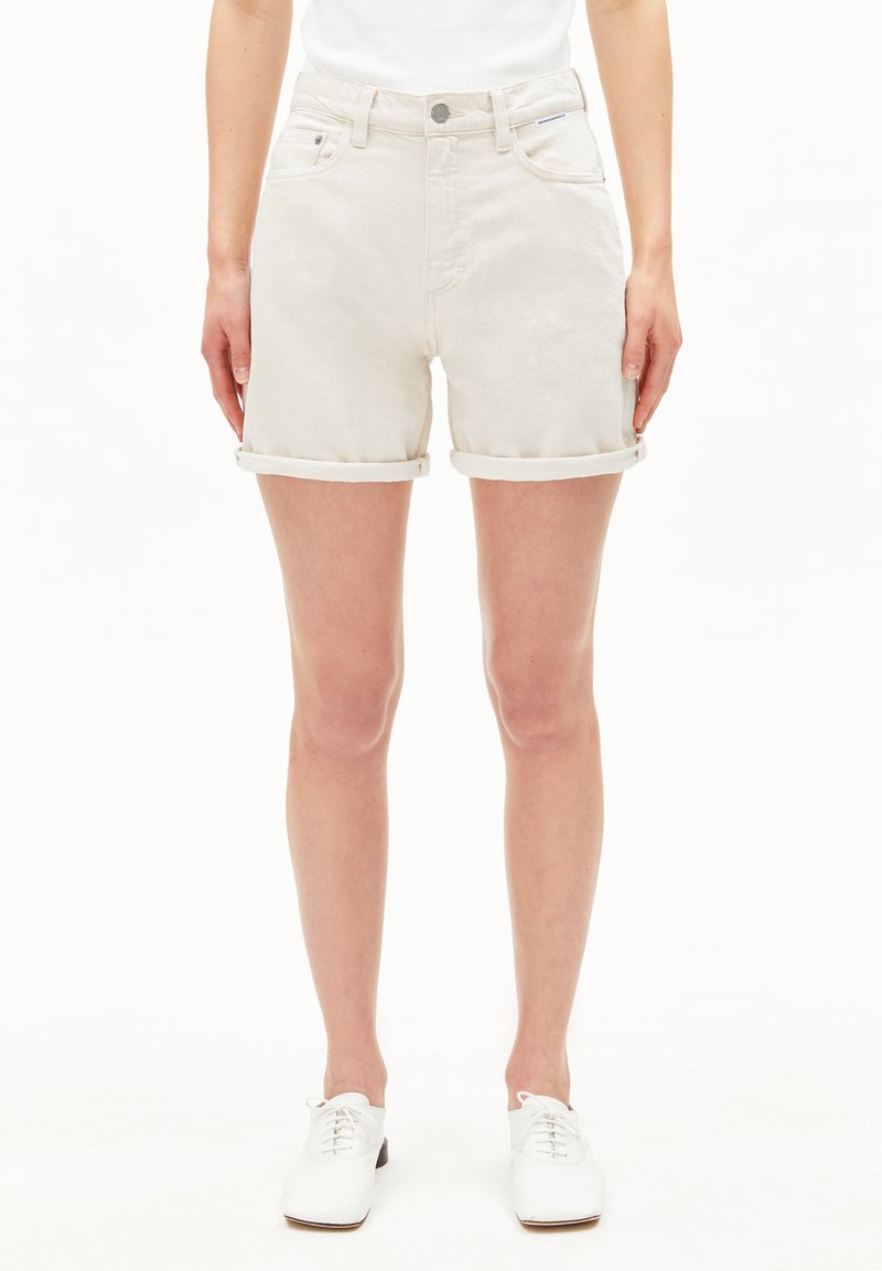 Lichtgrijze denim shorts met opgerolde zoom, frontzakken en een knoopsluiting. Gecombineerd met witte veterschoenen. Glad textuur.