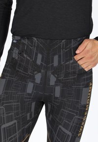 Schwarze Leggings mit einem geometrischen Muster in Grau, diamondförmige Taschen und "SWEDEMOUNT" Branding in Gold an der Seite.