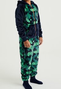 Mono de forro polar en azul marino oscuro con un patrón floral verde, con capucha, bolsillo frontal y puños elásticos en los tobillos.