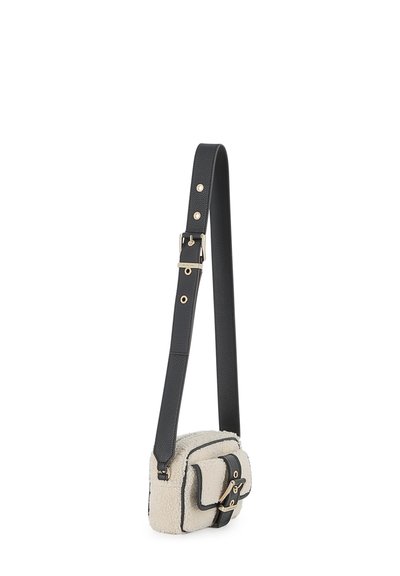 Juodas odinis crossbody krepšys su kreminės spalvos avių vilnos priekiu, su dangteliu, užsegamas užtrauktuku, ir auksinės spalvos detalėmis. Komplekte yra reguliuojama petneša.