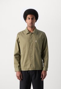 Olive green jacket in a lightweight, textured fabric with a collared neckline, front buttons, and a chest pocket featuring subtle branding.