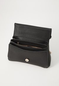 Borsa nera con texture e chiusura a patta, hardware dorato e più scomparti. L'interno presenta una foderatura in tessuto a contrasto.