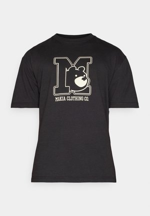 T-shirt nera a maniche corte con una grande lettera "M" contornata che presenta il volto di un orso all'interno e "Makia Clothing Co." stampato sotto.