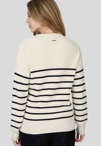 Pull crème avec des rayures horizontales bleu marine, texture côtelée et col rond. Présente une petite étiquette de marque à l'arrière.