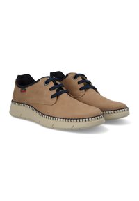Zapatos de cuero marrón con cordones azul marino, que presentan una superficie ligeramente texturada, punta redondeada y suelas de goma crema con detalles de costura en contraste.