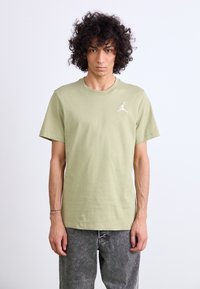 Lysegrøn bomulds T-shirt med korte ærmer og rund halsudskæring. Inkluderer et hvidt logo på venstre brystområde. Ret-skåret design.