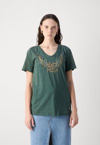 Zelené bavlněné tričko s véčkovým výstřihem, zdobené vyšitými křídly a textem "Rock & Roll" v metalické nitě. Krátké rukávy, volný střih.